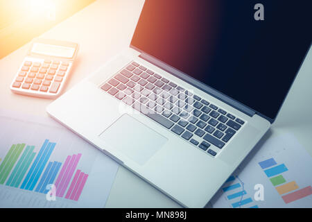 Graphs, charts and calculator on business table. workplace of business people with sunlight . Stock Photo
