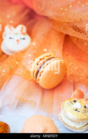 Orange macaroons with chocolate filling on orange tulle background Stock Photo