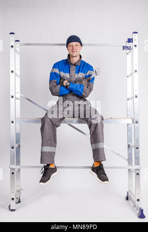 The builder, the installer sits at a height with a tool in his hands. Stock Photo