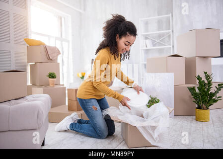 Adorable curly-haired girl unpacking plates Stock Photo