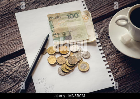 Polish money on the table, notes and coins.  Piece of paper and pencil. Coffee. Stock Photo