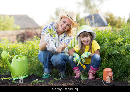 Mother and daughter planting strawberry seedlings in summer time
