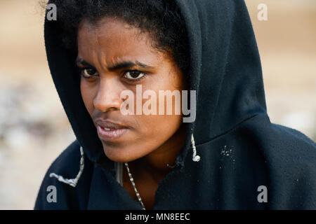 DJIBOUTI , Obock, from here ethiopian migrants try to cross bab el mandeb by boat to Yemen to go on to Saudi Arabia or Europe, ethiopian refugees from Tigray waiting outside the town for the smugglers, ethiopian orthodox christian with cross scar on the forehead / DSCHIBUTI, Obock, Meerenge Bab el Mandeb, mit Hilfe von Schleppern aethiopische Migranten versuchen hier nach Jemen ueberzusetzen, um weiter nach Saudi Arabien oder Europa zu gelangen, aethiopische Fluechtlinge aus Tigray warten ausserhalb der Stadt auf die Schmuggler, orthodoxe Christin mit auf der Stirn in die Haut eingeritztem Kre Stock Photo