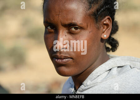 DJIBOUTI , Obock, from here ethiopian migrants try to cross bab el mandeb by boat to Yemen to go on to Saudi Arabia or Europe, ethiopian refugees from Tigray waiting outside the town for the smugglers, ethiopian orthodox christian with cross scar on the forehead / DSCHIBUTI, Obock, Meerenge Bab el Mandeb, mit Hilfe von Schleppern aethiopische Migranten versuchen hier nach Jemen ueberzusetzen, um weiter nach Saudi Arabien oder Europa zu gelangen, aethiopische Fluechtlinge aus Tigray warten ausserhalb der Stadt auf die Schmuggler, orthodoxe Christin mit auf der Stirn in die Haut eingeritztem Kre Stock Photo