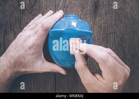 hand of male person putting money into piggy bank savings concept Stock Photo