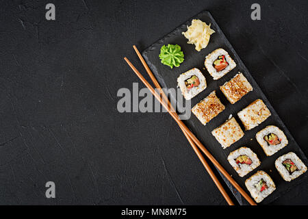 Traditional Japanese food - sushi, rolls and chopsticks for sushi on a dark background. Top view Stock Photo