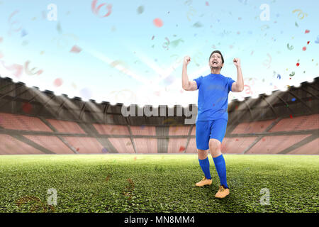 Attractive asian male football player celebrate victory in stadium Stock Photo