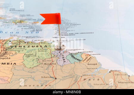 Small red flag marking the African country of Guyana on a world map. Stock Photo