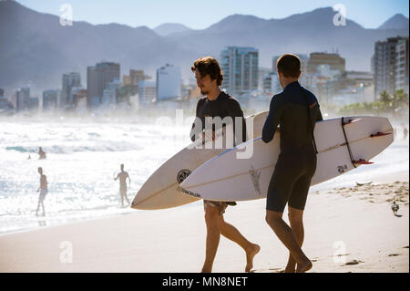 RIO DE JANEIRO - MARCH 20, 2017: Surfers stand on the beach before heading into the waves at the surf break at Arpoador. Stock Photo