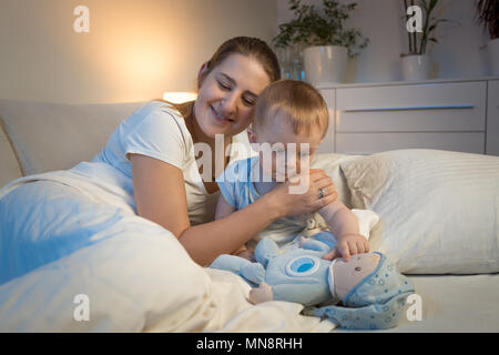 Young smiling mother hugging her baby son before going to sleep Stock Photo