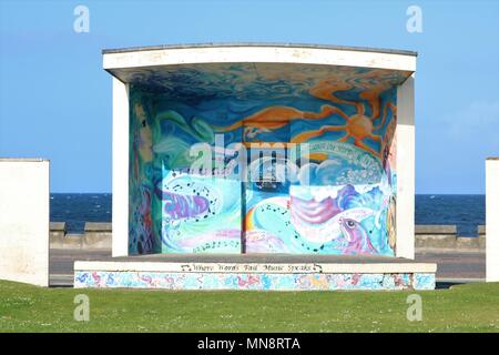 Shelter painted with art on seafront with sea in background against a blue sky at Ayr, Scotland, UK. Stock Photo