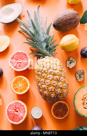 Organic exotic fruit a wallpaper over an orange board, top view,flat lay, ananas circled by watermelon ,mango, passion fruit cantaloupe melon, coconut Stock Photo