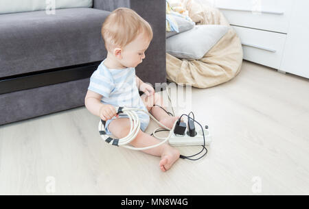 Unatteded little baby boy playing with electric power cables. Child in dangerous situation Stock Photo