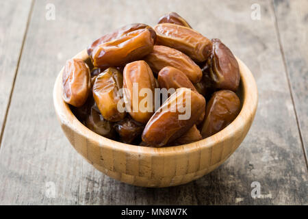 Dates in wooden bowl on wooden background Stock Photo