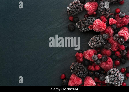 Frozen summer berries on a slate background, blackberry raspberry, red and black currants. Stock Photo