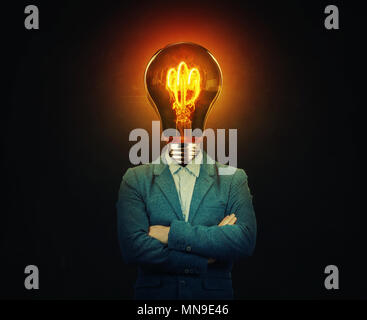 Surreal image as a serious businessman with a bulb instead of his head with crossed hands over black background. Business idea and creativity symbol. Stock Photo