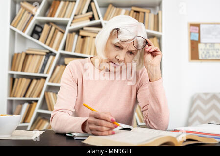 Attentive senior woman having trouble in study Stock Photo