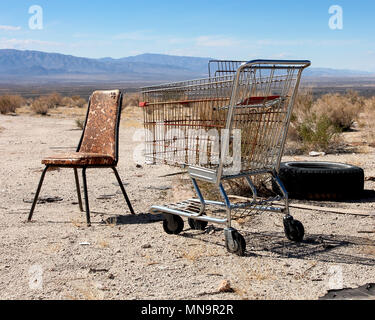 An old chair, shopping trolley, tire, an unlikely still life grouping looks across California's Wonder Valley, in the High Desert, the Mojave, USA. Stock Photo