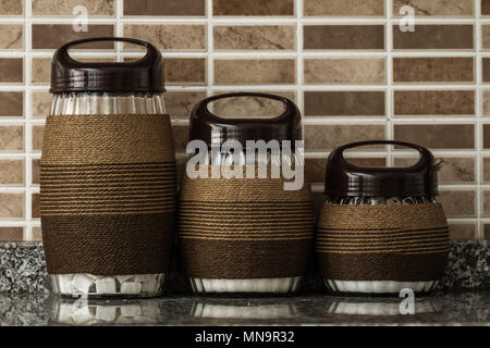 Rope wrapped decorative glass jars on brown background Stock Photo