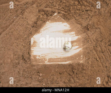 Baseball laying with homeplate on dirt field for game. Stock Photo