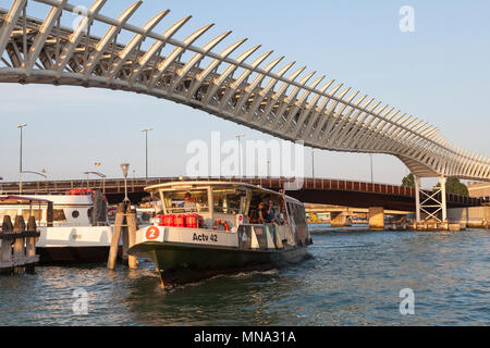 No:2 vaporetto (waterbus) on the Grand Canal passing under the elevated people mover tracks at sunset, Venice, Veneto, Italy. Public transport by boat