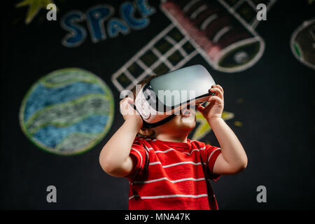 A portrait of a child playing with a virtual reality headset. A young boy wearing and learning with a VR glasses. Stock Photo