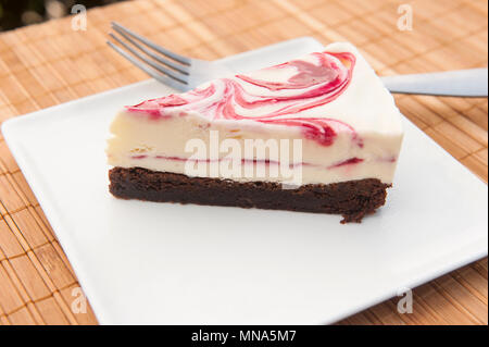 Slice of raspberry ripple ice cream cake on a white plate Stock Photo