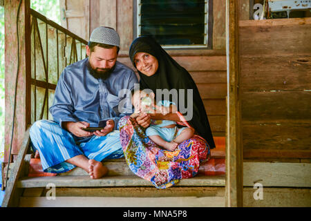 Krabi, Thailand - May 2, 2015: Muslim family feeding milk to their child together in their home in Krabi, Thailand Stock Photo