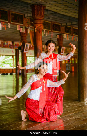 Kanchanaburi, Thailand - July 23, 2016: Beautiful teenage girls dancing to show tourists in wooden Buddhist pavilion in Kanchanaburi, Thailand Stock Photo