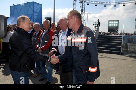 Russian President Vladimir Putin greets construction workers before climbing behind the wheel of a Kamaz dump truck during the opening ceremony for the Crimean Bridge motorway May 15, 2018 in Taman, Kerch, Russia. Putin drove the lead vehicle in a construction equipment convoy marking the inauguration of the project linking Russia with Crimea.  (Russian Presidency via Planetpix) Stock Photo