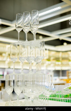 empty glasses in pyramid or tower on table at wedding reception, alcohol bar, catering in restaurant.Pyramid of champagne glasses Stock Photo