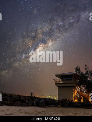 Milky Way Core over Noosa Main Beach & one of the Surf Life Saving Towers situated at the Groyne Rock Wall Stock Photo