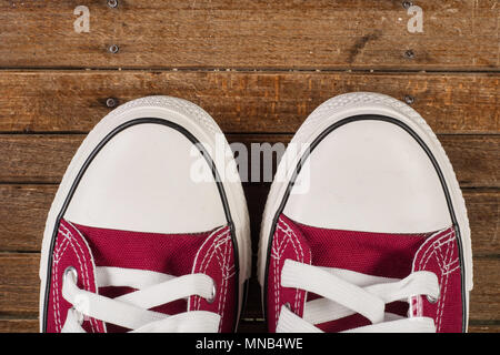 Pair of red sneakers on old retro wooden background. Close up. Retro fashion concept. Stock Photo