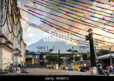 San Juan del Obispo, Guatemala - December 26, 2015: Locals outside one of oldest Catholic churches in Guatemala with Agua volcano behind. Stock Photo