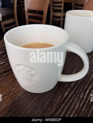 Cup of tea with Starbucks logo on a table with chairs in the background Stock Photo