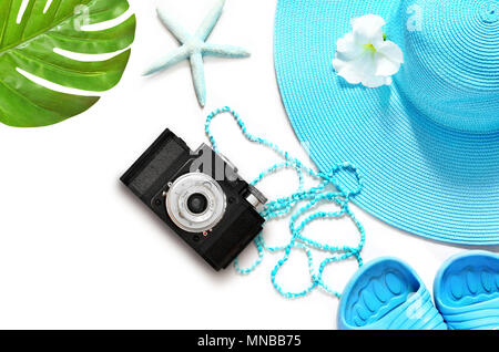 Vintage camera on white surface with beach items and palm, top view. Stock Photo