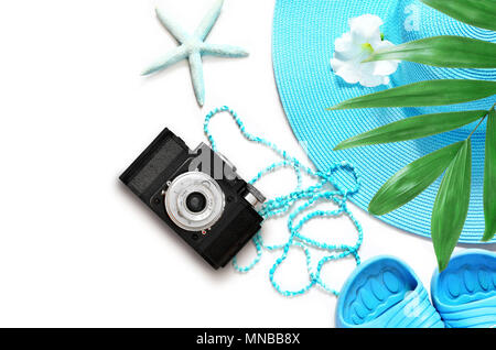 Vintage camera on white surface with beach items and palm, top view. Stock Photo