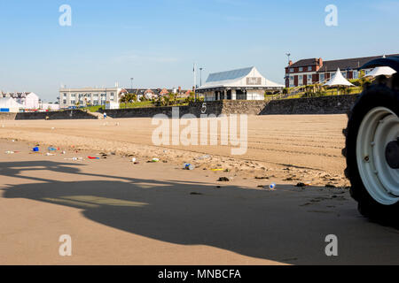 Sandy beach at Whitmore Bay, Barry Island with litter about to be cleaned by tractor the front wheel and shadow of which are in shot. Stock Photo