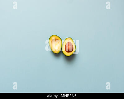 Avocado sliced with seed isolated in blue background viewed from above - flatlay look Stock Photo