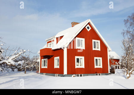 Two stories Swedish older red family house with basment with a snow covered garden during the winter season. Stock Photo
