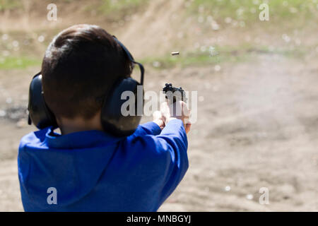 A boy safely practices shooting a pistol at a range in north Idaho. Stock Photo