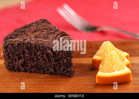 A close up image of rich chocolate cake and orange wedges on a board. Stock Photo