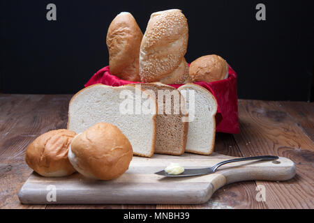 Assorted breads such as sliced bread, rolls, and baguettes on display. Stock Photo