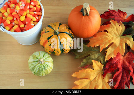 Colorful fall leaves pumpkin and white bucket of candy corn. Stock Photo