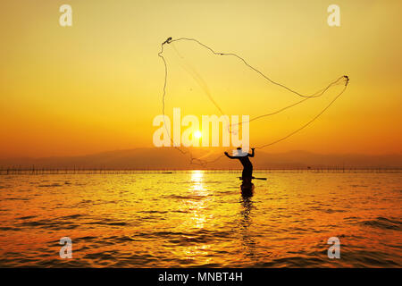 Young fisherman throwing his net during the sunset Stock Photo - Alamy