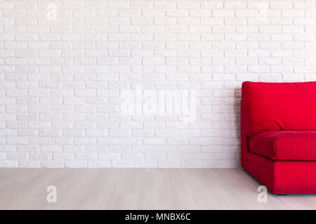 Red sofa standing in room with light flooring and decorative, white brick wall Stock Photo