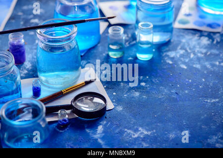 Artist workplace with watercolor sketches in shades of blue. Monochromatic painting with glass jars, paint and brushes. Drawing sea concept with copy  Stock Photo