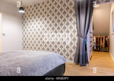 Bedroom with wallpaper, bed and walk in wardrobe Stock Photo