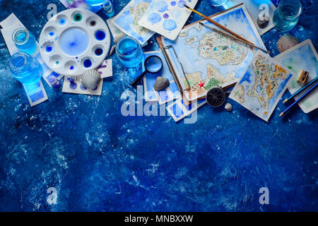 Artist workplace with a watercolor map, sketches, seashells and compass on a navy blue background with copy space. Travel flat lay header. Stock Photo