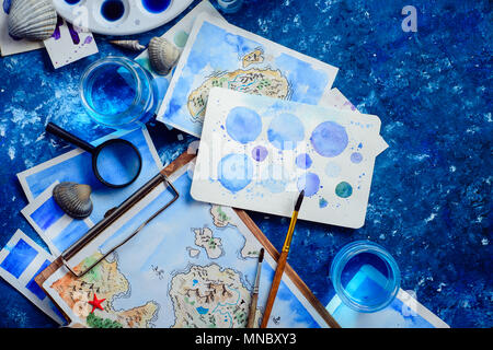 Artist workplace with a watercolor map, sketches, seashells and compass on a navy blue background with copy space. Travel flat lay header. Stock Photo